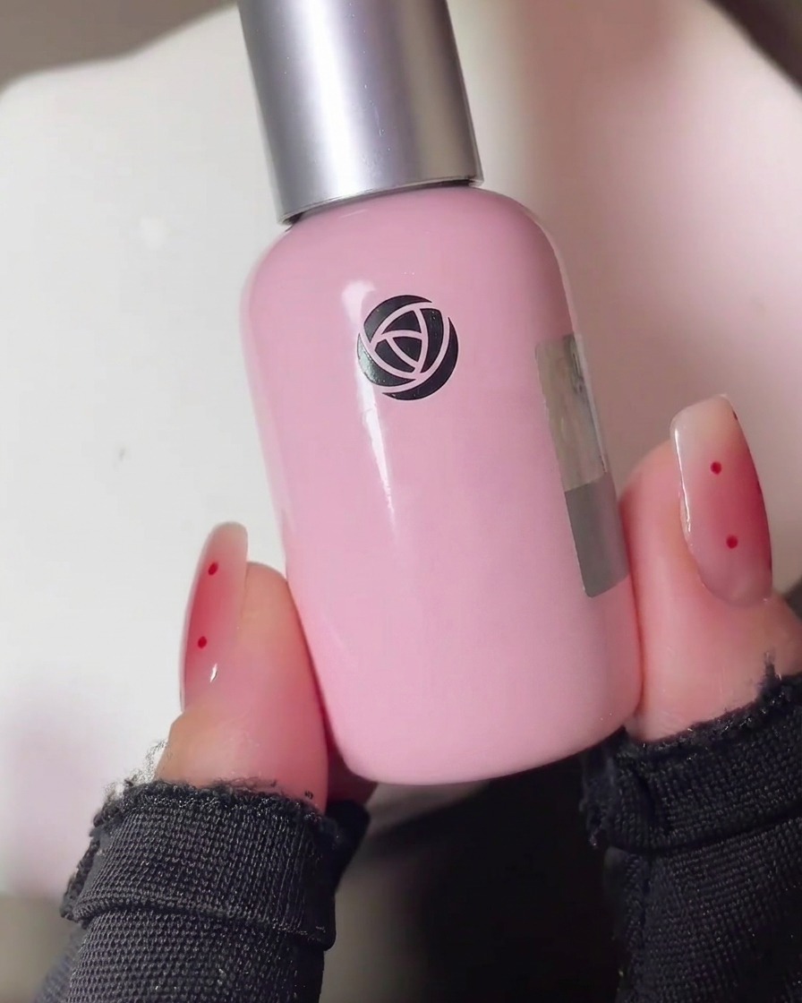 A hand with gel-painted nails placed inside a professional UV nail lamp for curing.