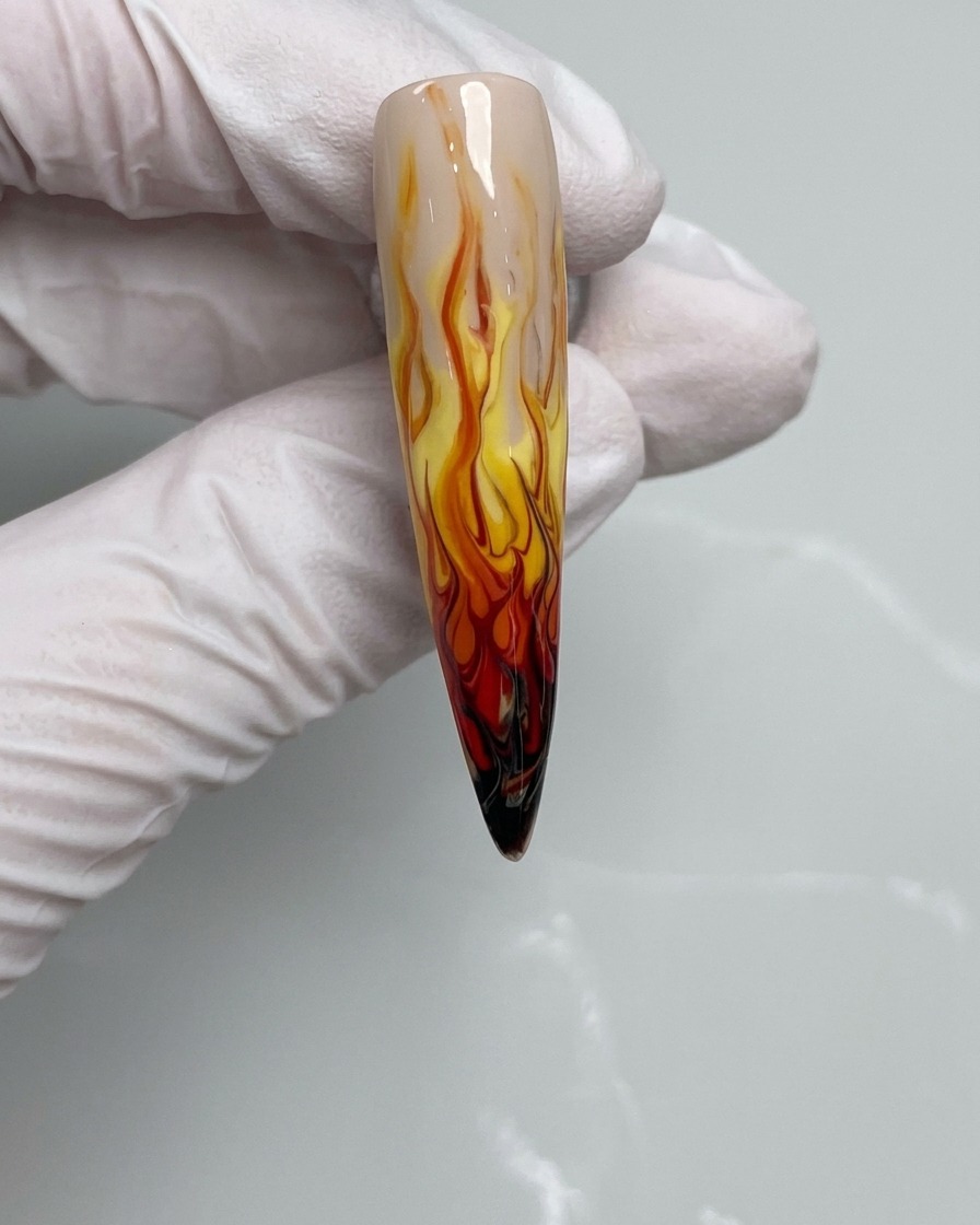A nail brush applying black gel polish to the tip of a fingernail.