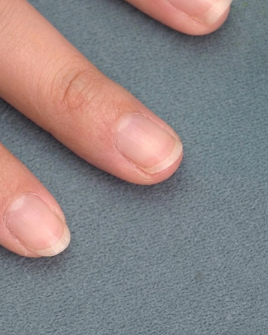 A soft brush removing stray metallic dust from a nail.