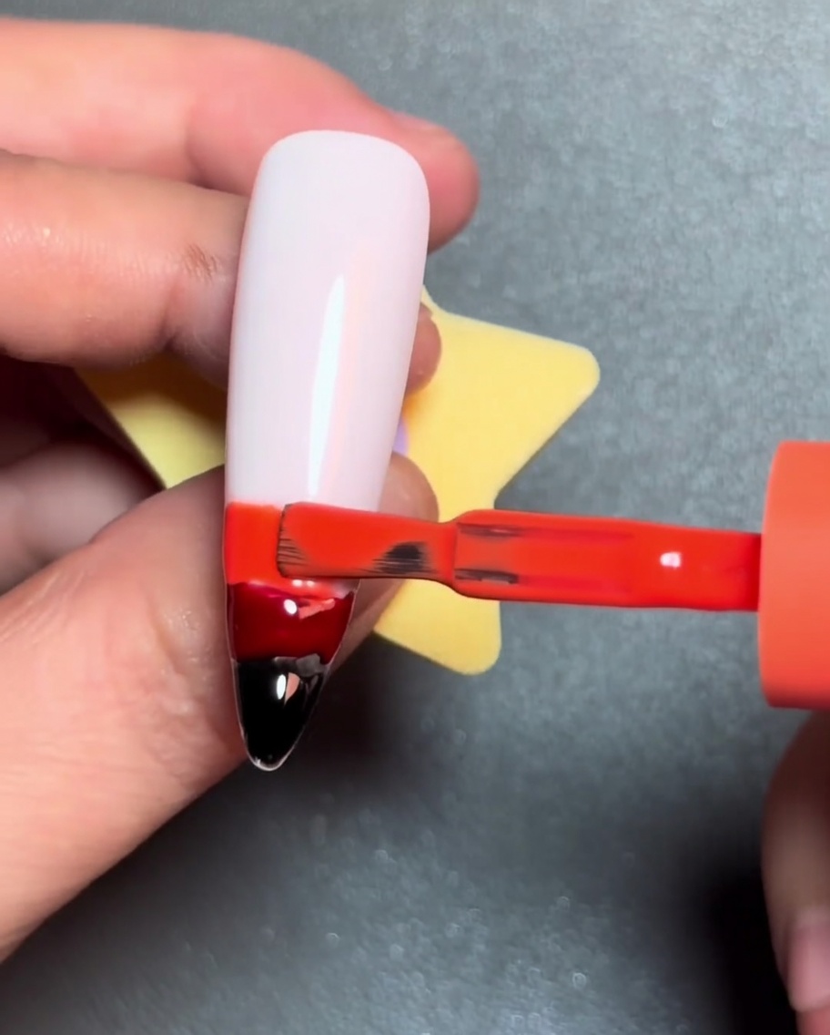 A brush applying a yellow line of gel polish above the orange gel stripe.