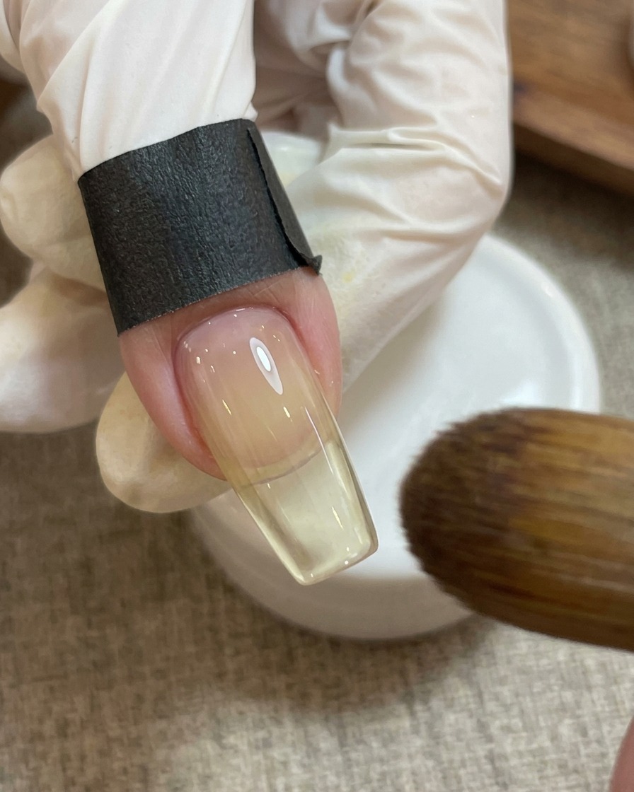 A nail magnet held over the pink heart design on the nail to create a shimmery effect.