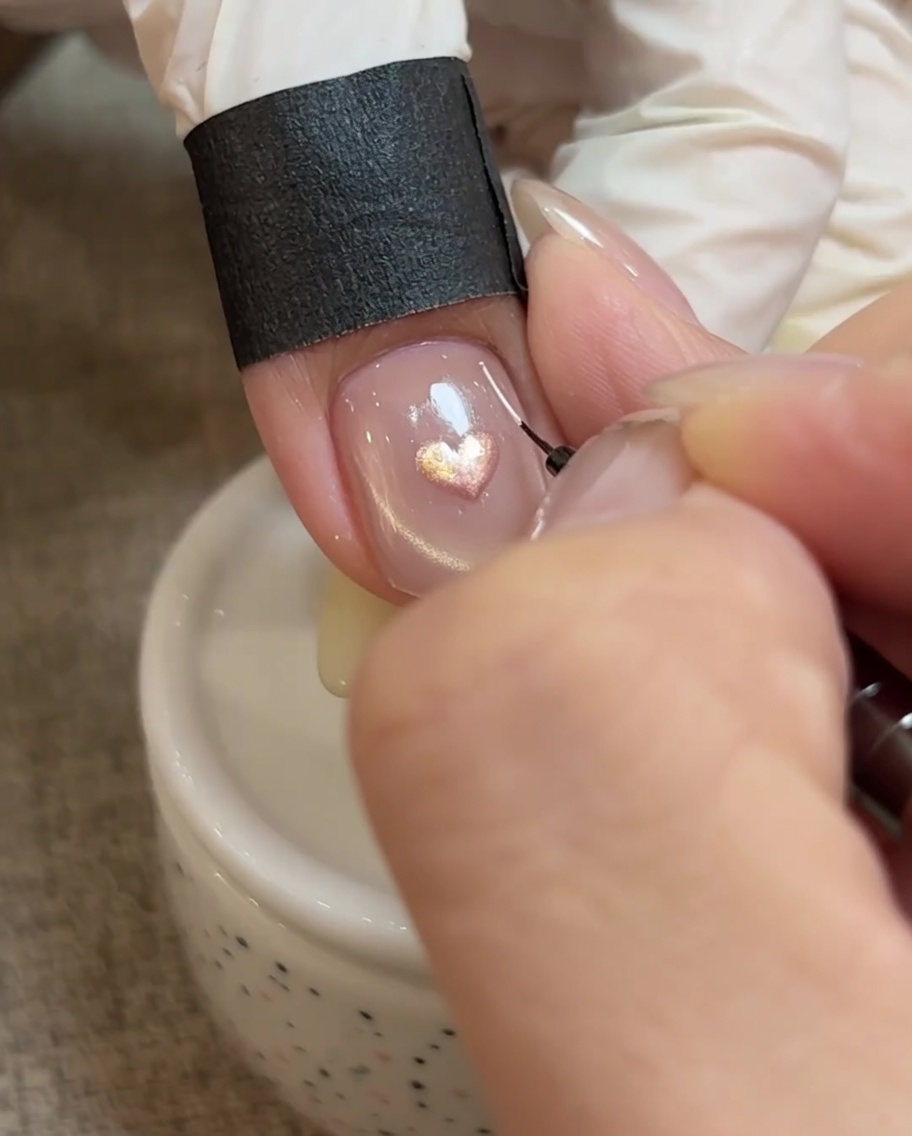 A liner brush adding fine white detail lines radiating from the heart design.