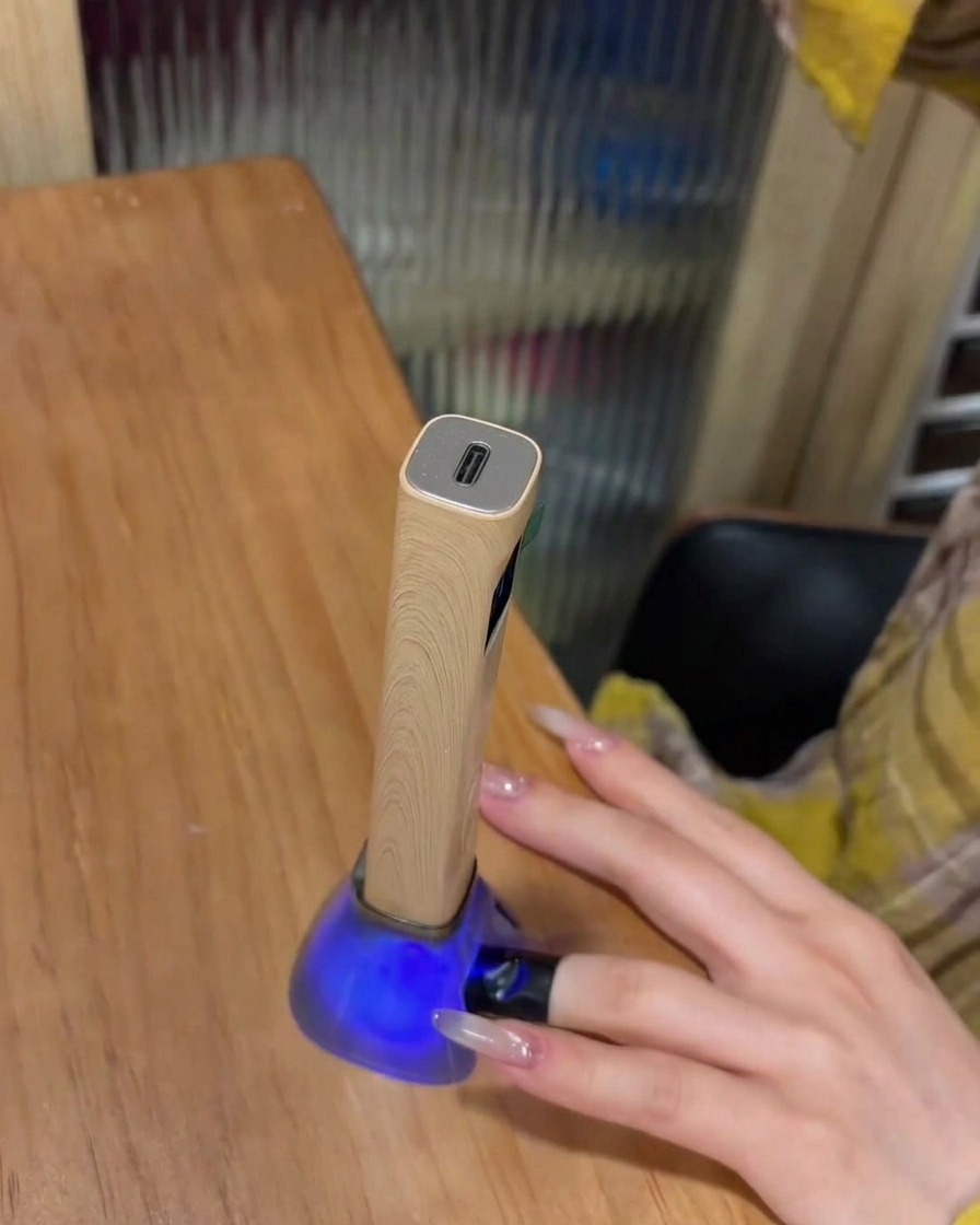 A finger with a placed rhinestone charm sitting inside a UV lamp for curing.