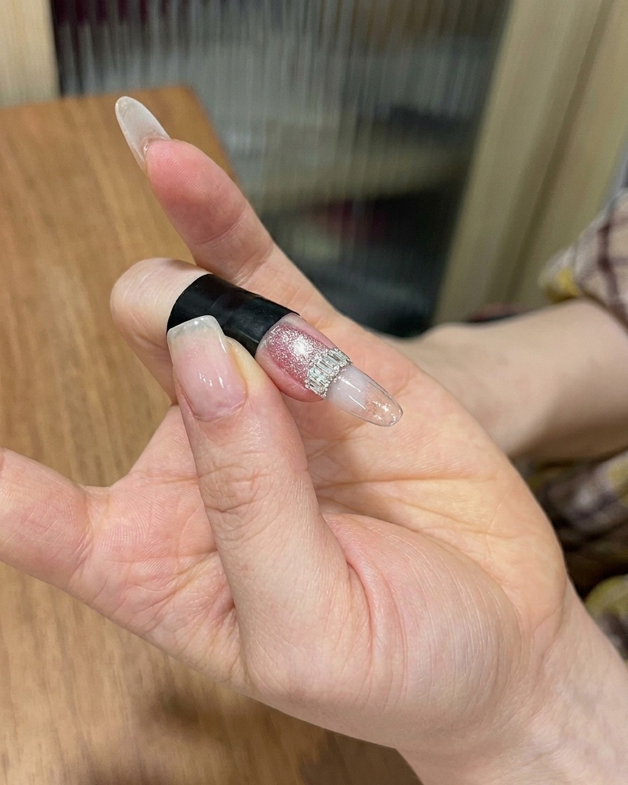 A hand positioned inside a professional nail lamp, with the focus on the nail receiving the final cure.