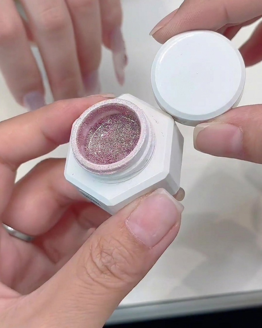 A detail brush applying silver glitter gel along the edge of a cat-eye French tip.