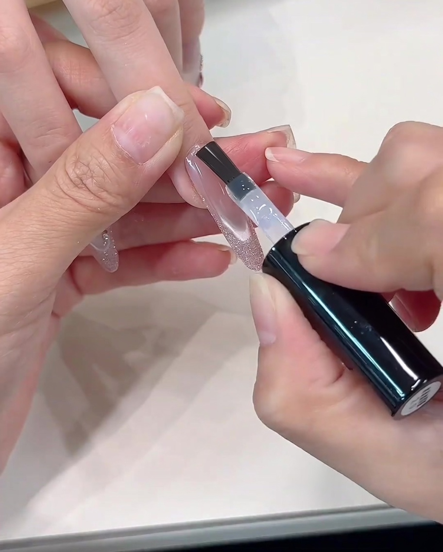 A clear top coat being applied over the finished glitter French design.