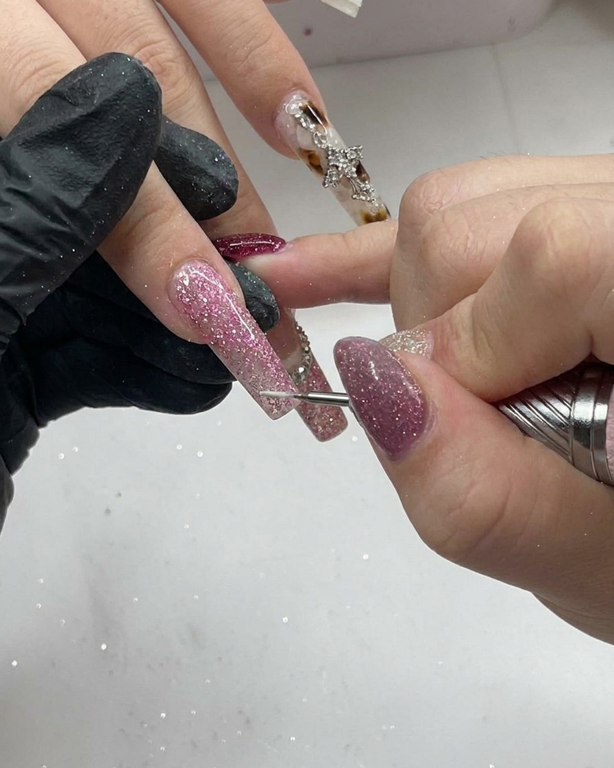 A detail brush painting a crisp, white French tip onto a natural-looking nail surface.