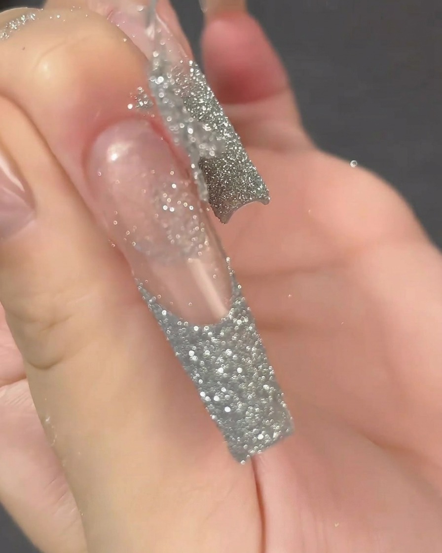 A close-up shot of a lint-free wipe cleaning the surface of a long, clear, prepped nail extension.