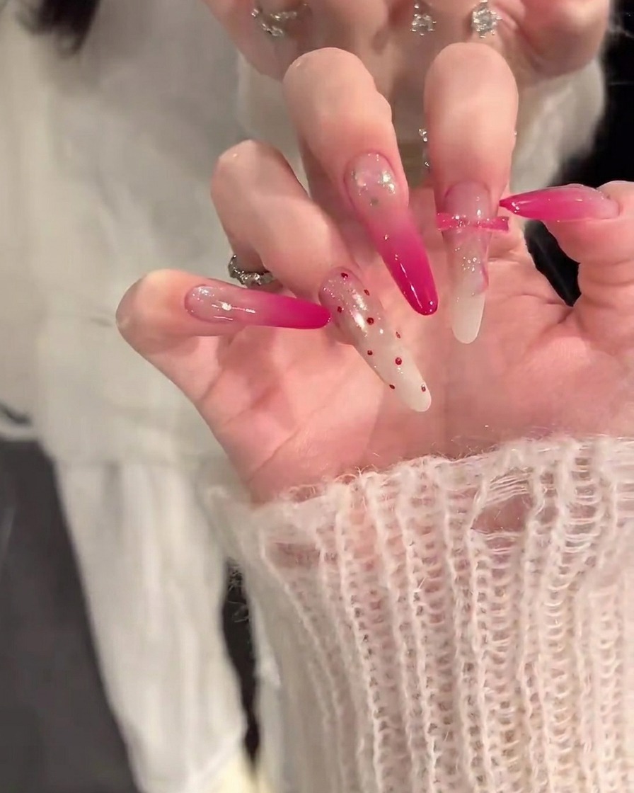A close-up of a hand with a nail brush applying a nude-colored base coat to clean, prepped fingernails.
