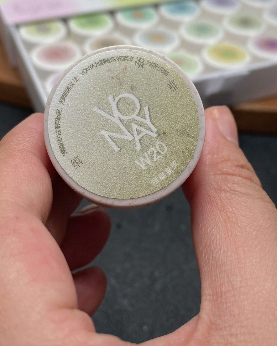 A brush applying a shimmering white cat-eye gel onto a nail, covering the entire nail surface evenly.