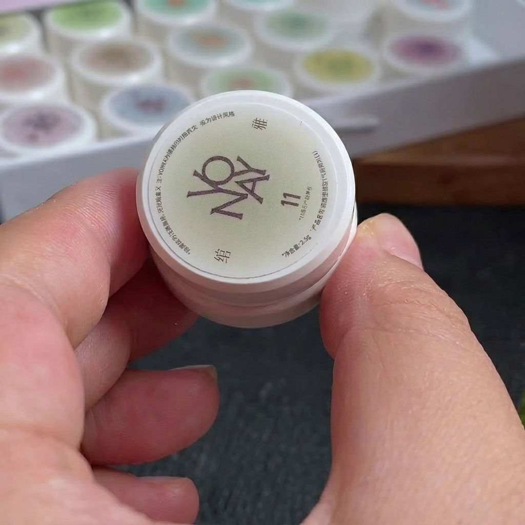 A small makeup sponge with lines of white and rose-red gel polish applied to its surface.