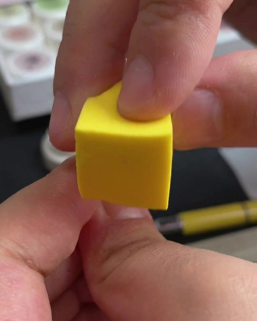 A hand placing nails under a professional UV/LED nail lamp for curing.