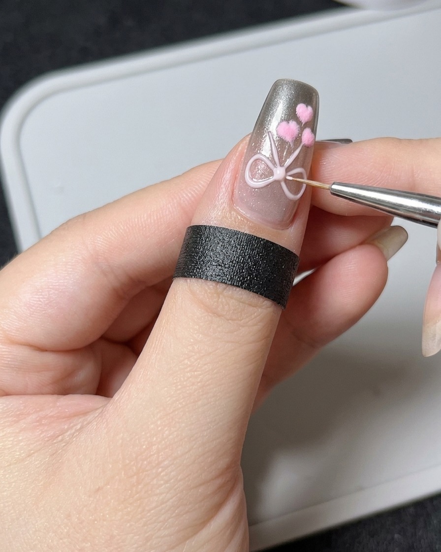 A fine liner brush adding a precise bead of thick 3D sculpting gel over an existing bow design on a nail.