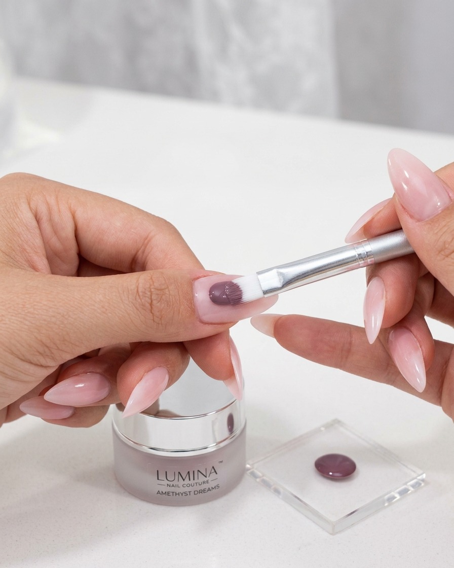 A small brush applying a rich-colored cat-eye gel polish to a prepared nail surface.