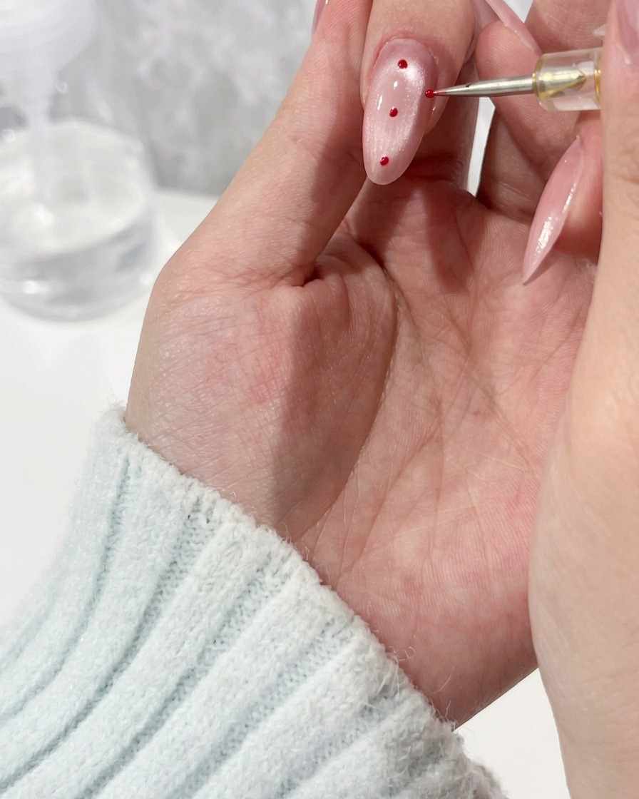 A close up view of a detail brush applying a bead of clear gel onto a manicured fingernail.