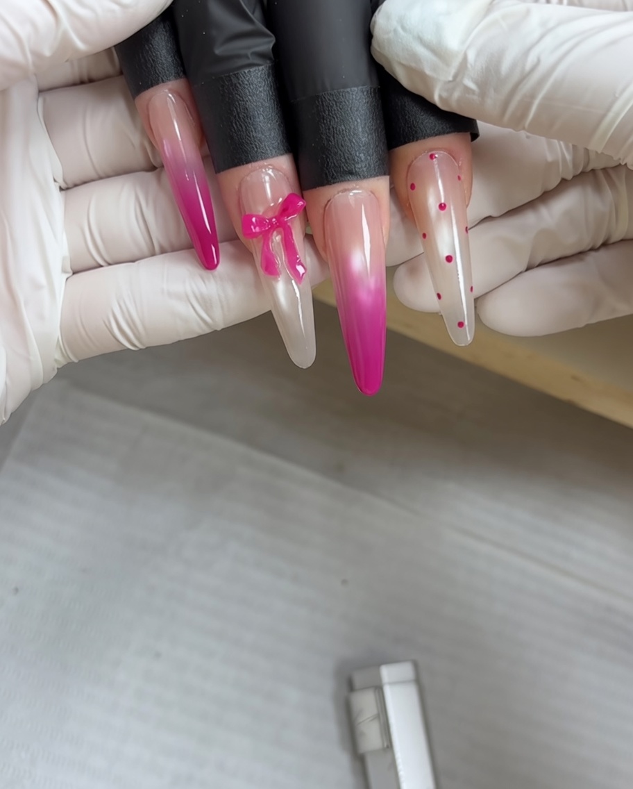A dotting tool applying tiny pink dots onto a cured metallic grey nail surface.
