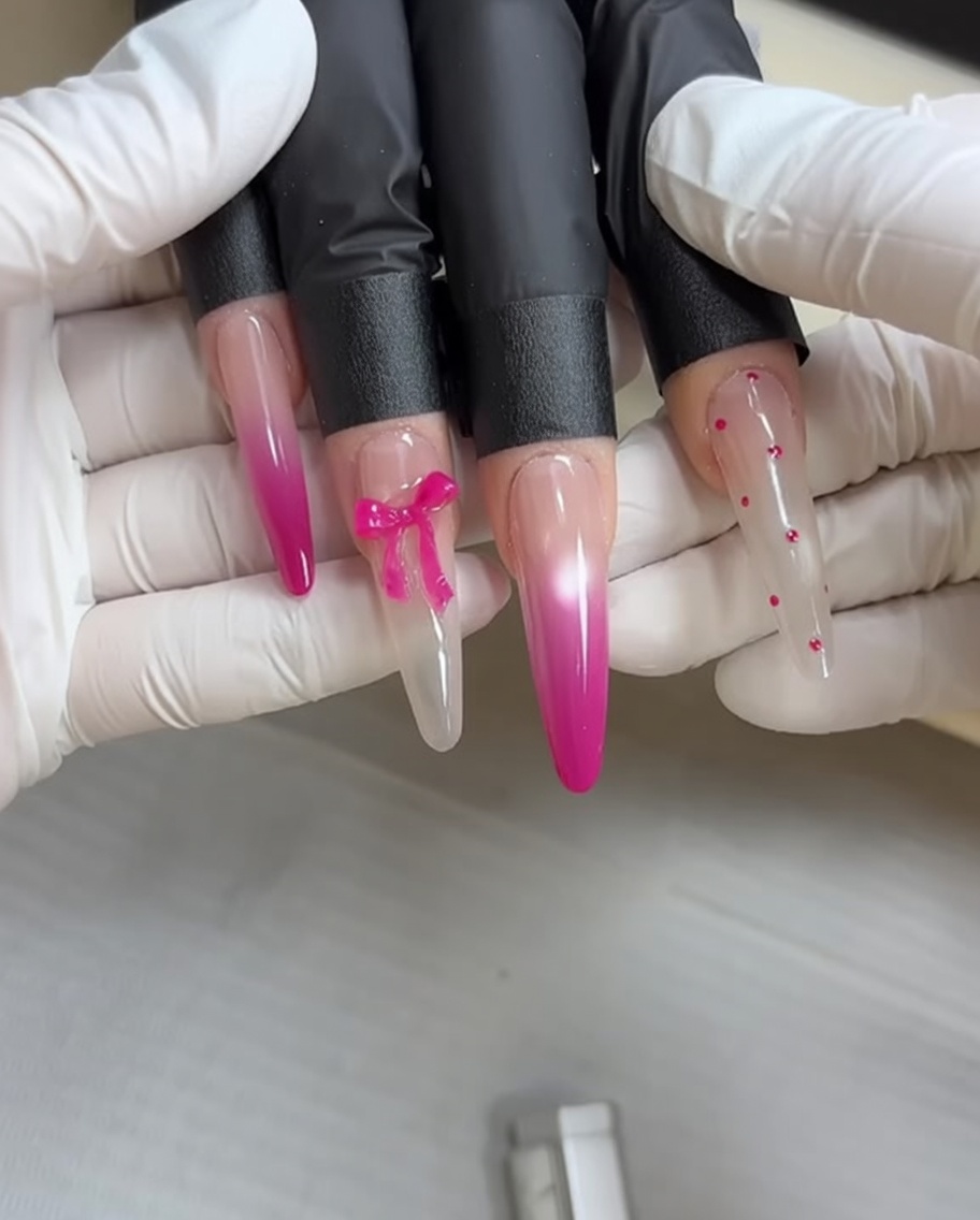 A makeup sponge applying pink gel polish to a nail to create a smooth ombre gradient effect.