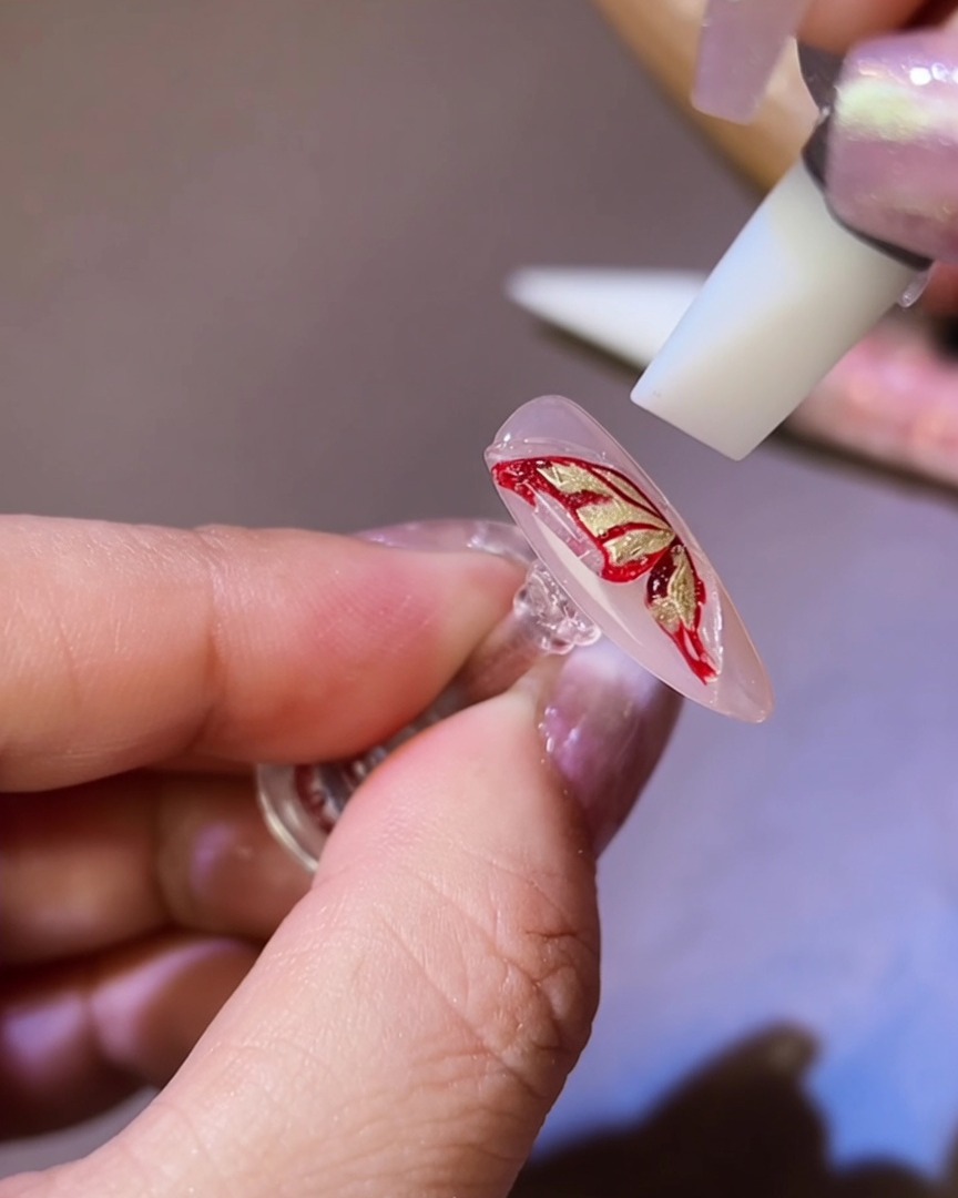 A silicone tool shaping the 3D gel into a butterfly wing silhouette on the nail.