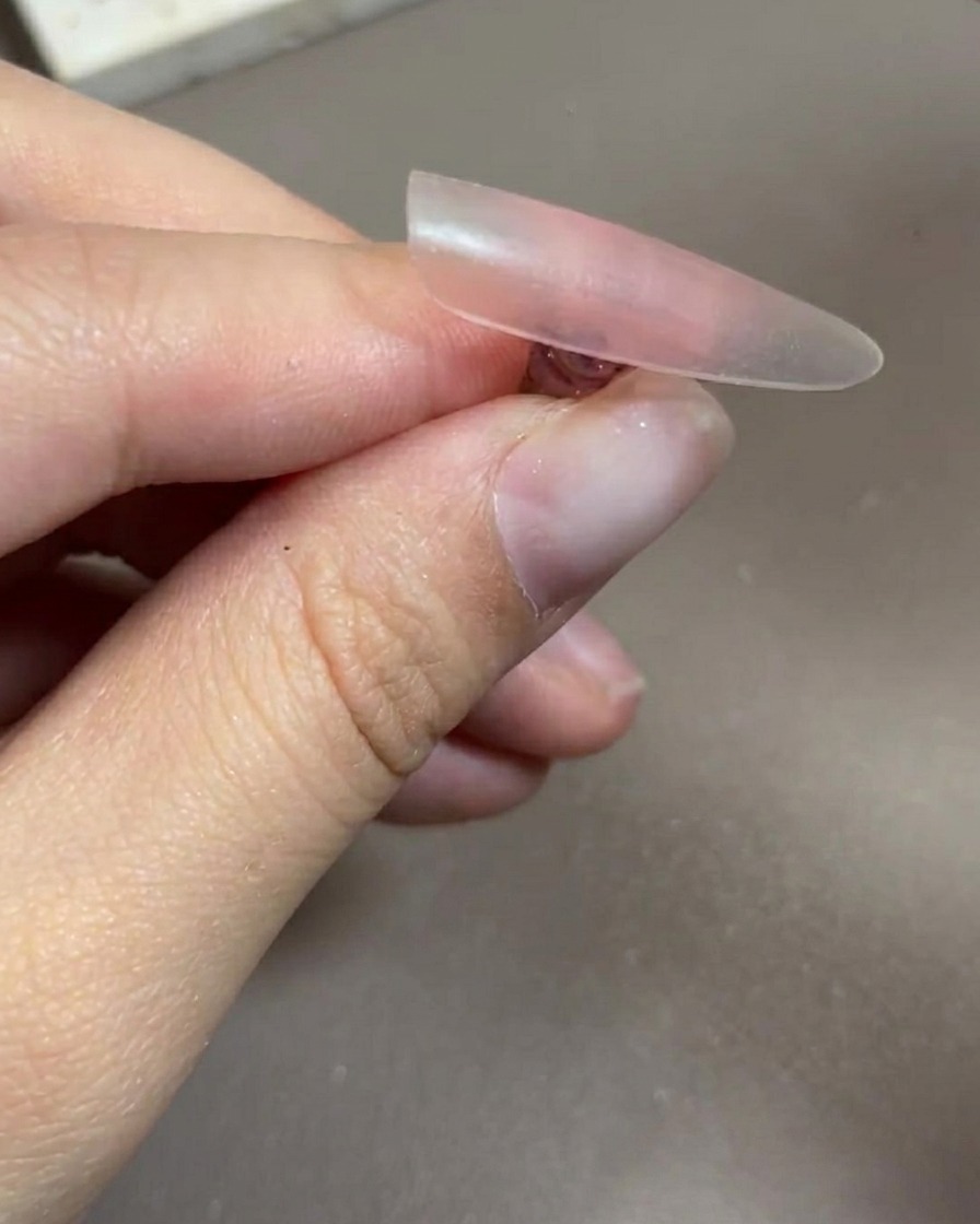 A hand placed inside a professional UV/LED nail lamp, with the nails fully visible under the light.