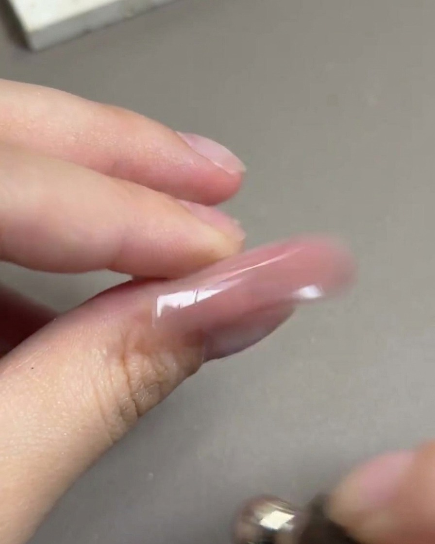 A magnetic tool being rotated in a circular motion around a nail to form a glowing spherical highlight.