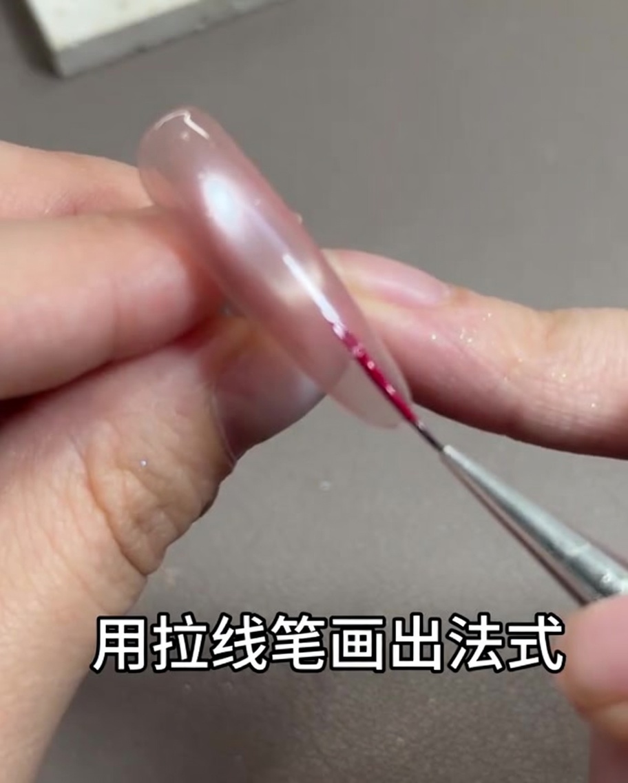 A thin nail art liner brush drawing a delicate rose red line along the free edge of the nail.