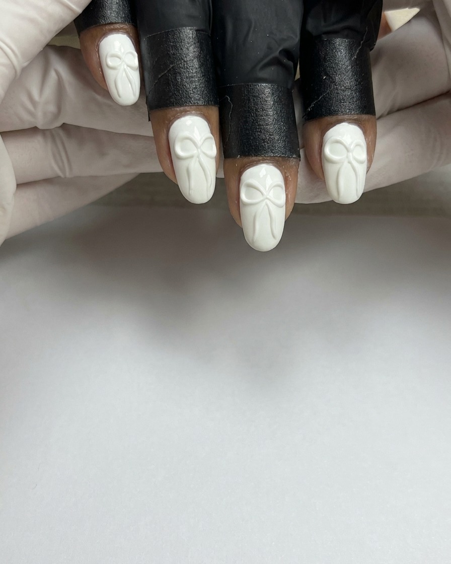 A nail brush applying a smooth coat of white gel polish onto a natural, prepped fingernail.
