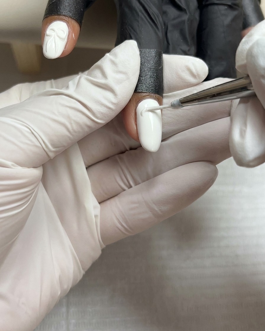 A small, precise bead of thick white sculpting gel resting in the center of a white painted nail.