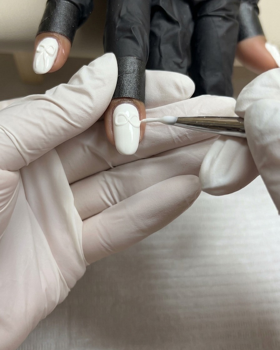 A fine brush shaping the second wing of a 3D gel bow to match the first.