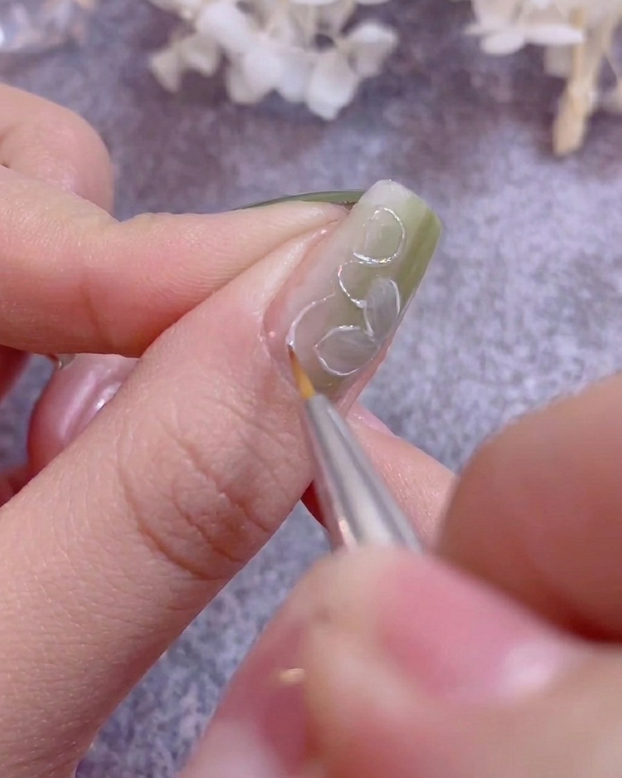A hand resting under the purple light of a UV/LED nail lamp curing gel polish.