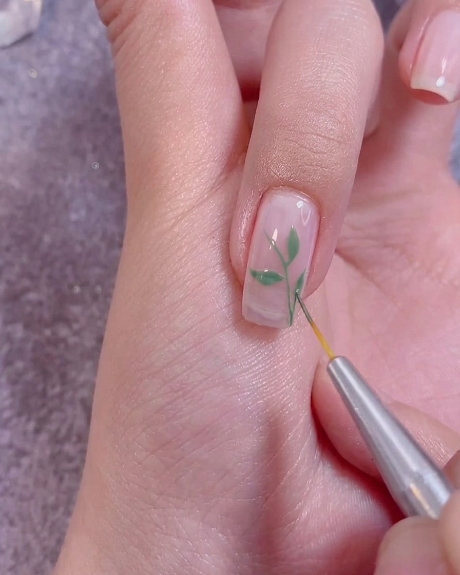 Applying a clear top coat over finished nail art with a professional nail brush.