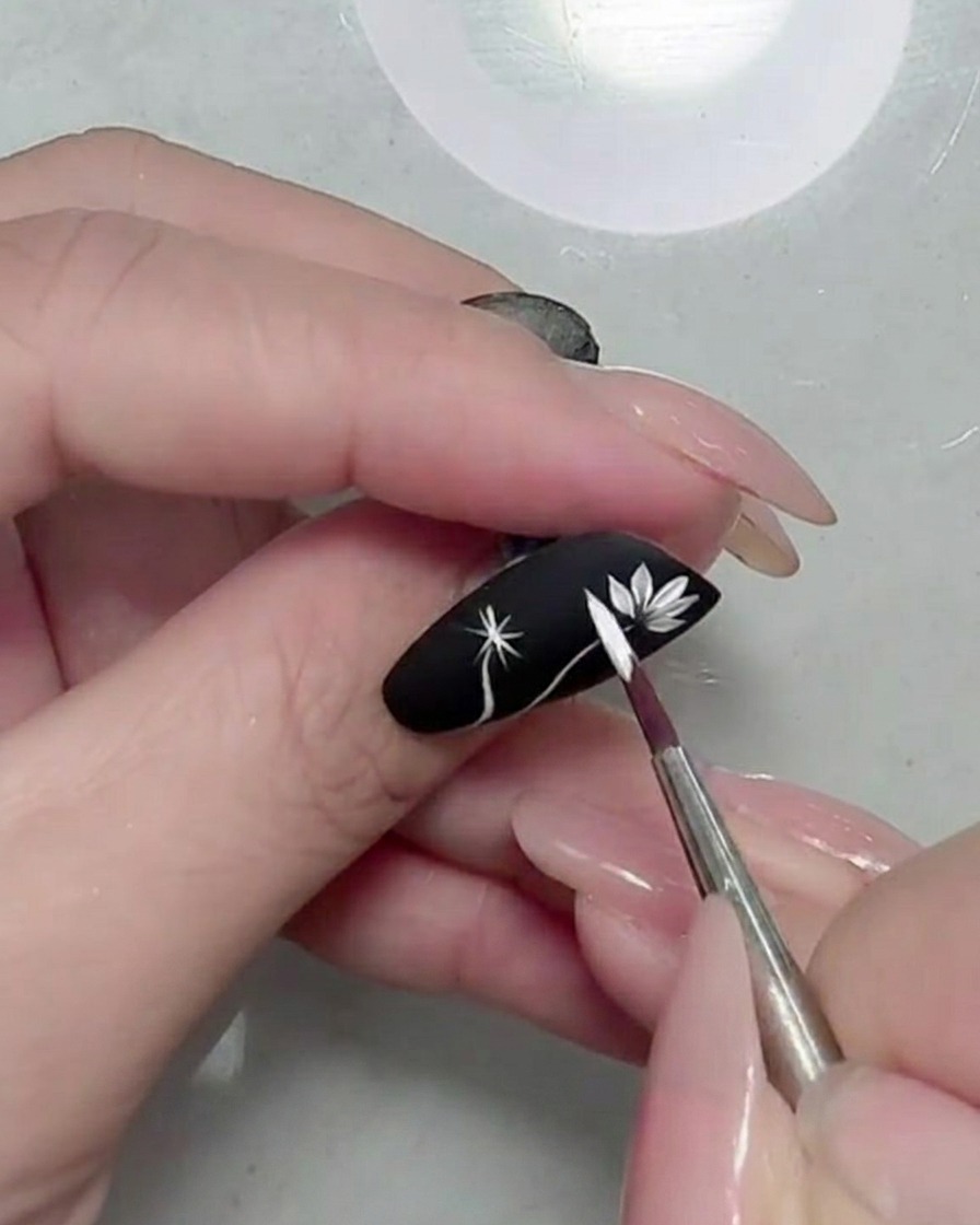 Close-up of a fully formed white daisy flower on a black matte nail.