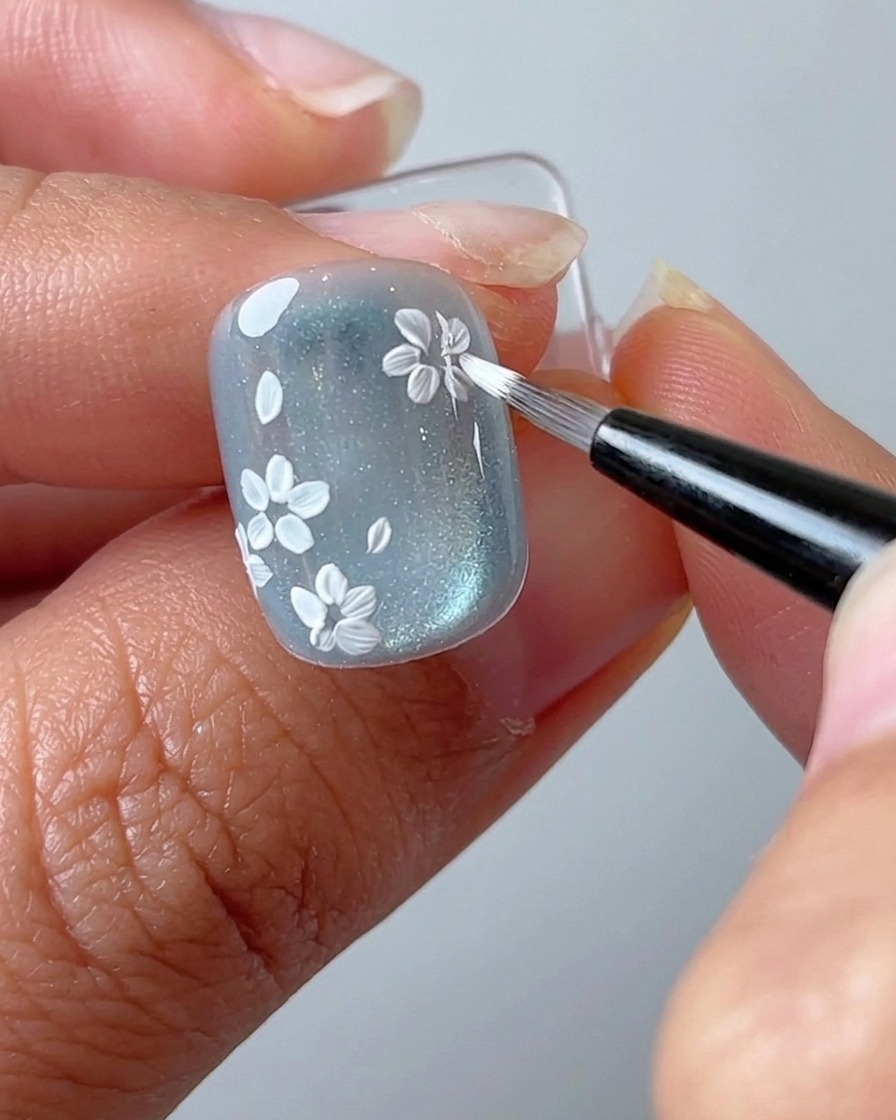 A liner brush adding a new flower cluster to an empty area of the nail.