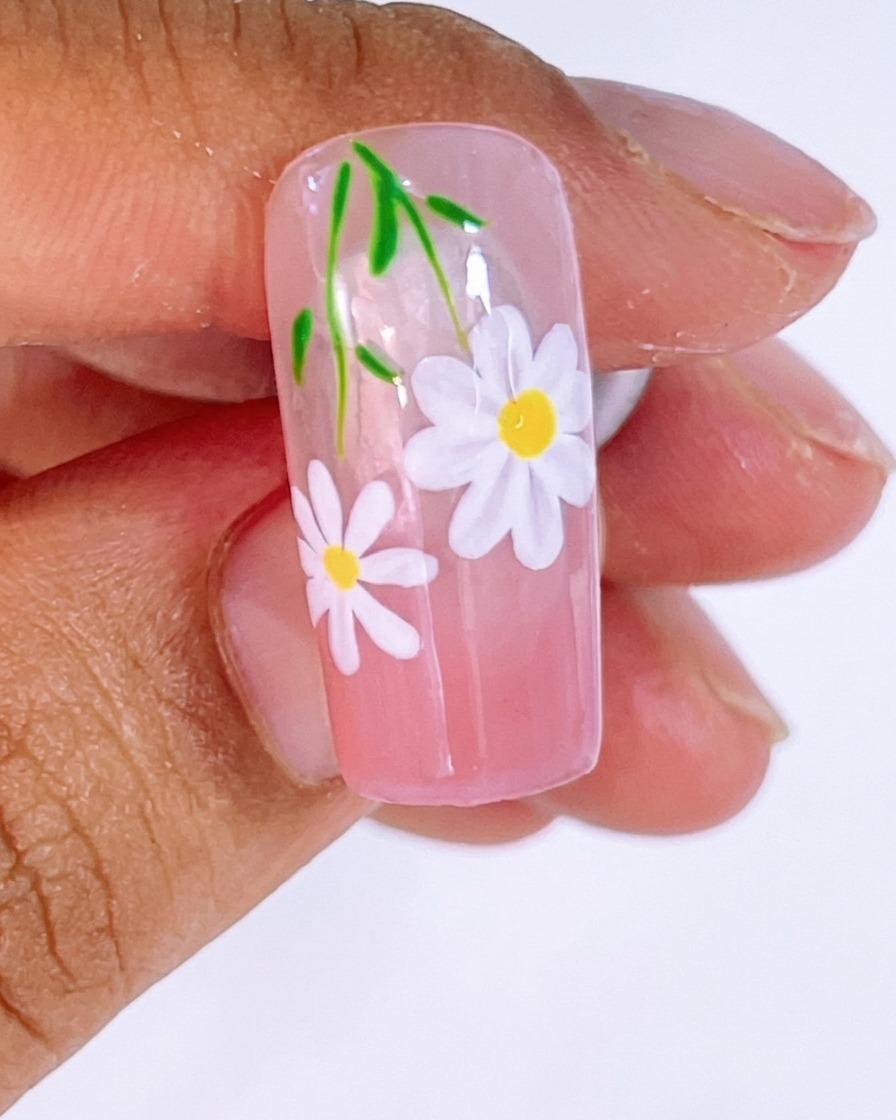 White gel being applied with a liner brush to form daisy petals over the guide lines.