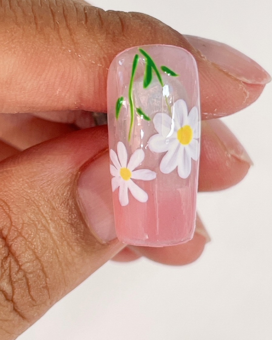 A nail tip placed inside a UV lamp for curing the freshly painted white petals.