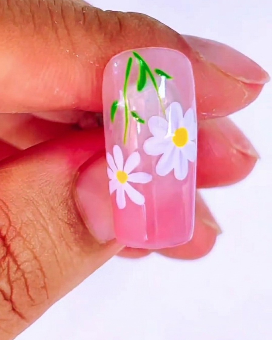 A dotting tool applying a small yellow dot to the center of the white daisy.