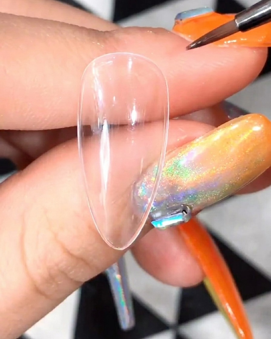 Close-up of a detail brush applying white gel to form the initial petal shapes for a daisy design on a clear nail tip.