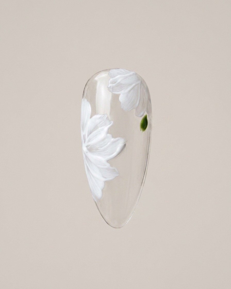 A detail brush carefully painting small green leaf accents in the gaps between the daisy petals.