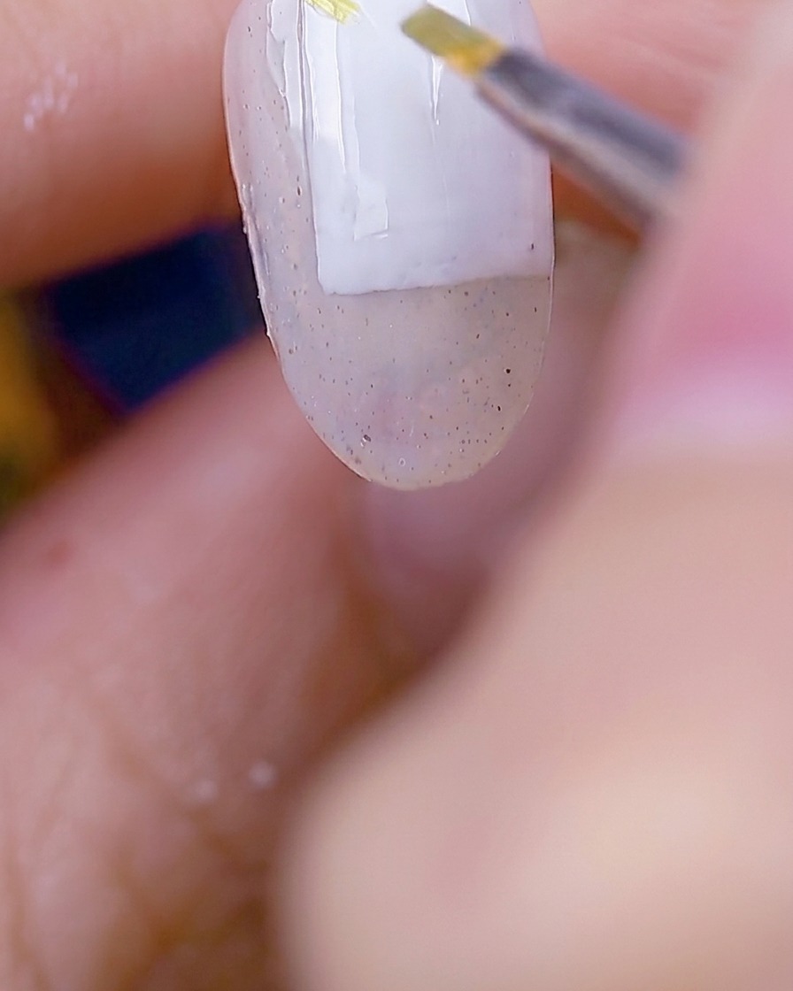 A brush applying moss green gel to create delicate leaf shapes over the prepped nail surface.