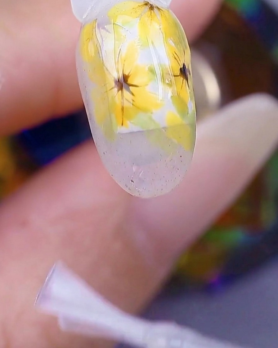 A close-up view of a hand inside a UV/LED nail lamp, with the nail surface appearing glossy and wet under the light.