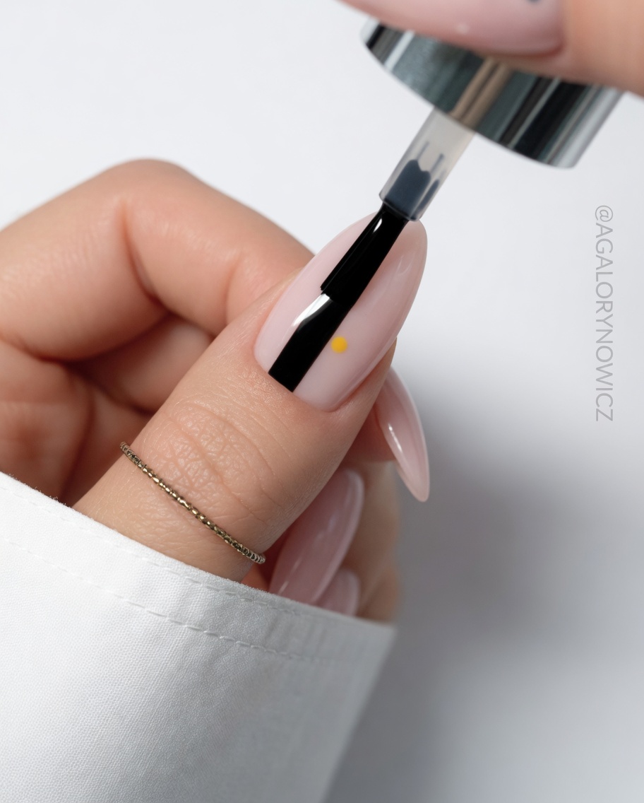 Detail shot of a third white petal being painted onto the nail.