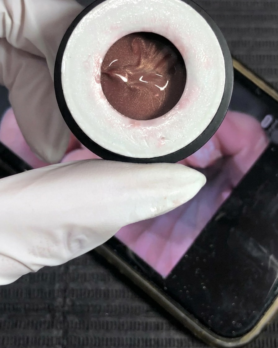 A close-up of a pot containing champagne-colored cat-eye gel polish.