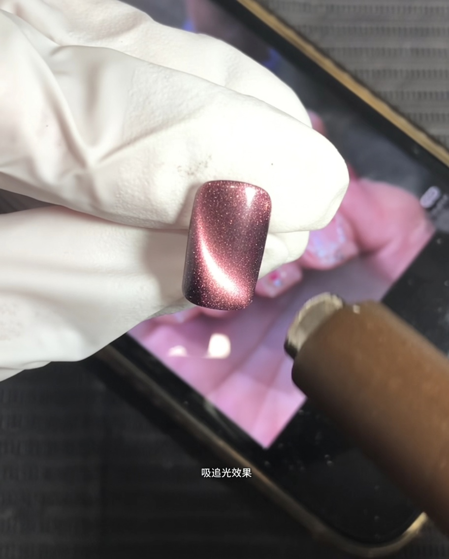 A magnet being held over a nail coated with cat-eye gel to create a bright, centered highlight.