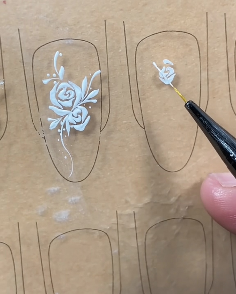 A liner brush completing the center bud by drawing a mirrored curved line on the right side.