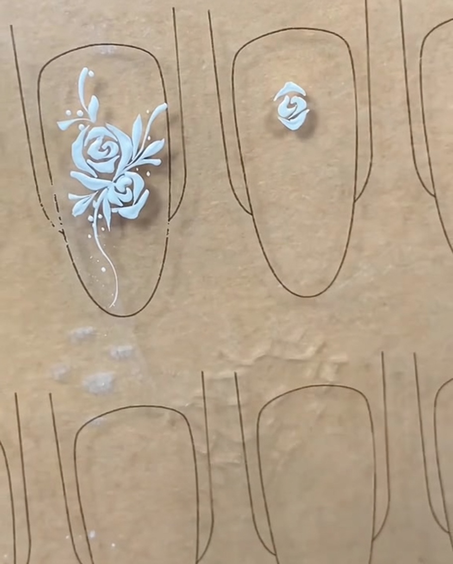 A liner brush drawing an arc-shaped petal line across the top of the established center bud.