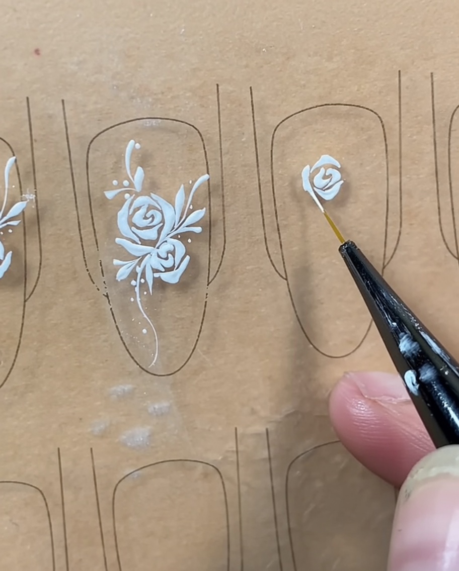 A liner brush adding a curved line beneath the center bud to close the rose shape.