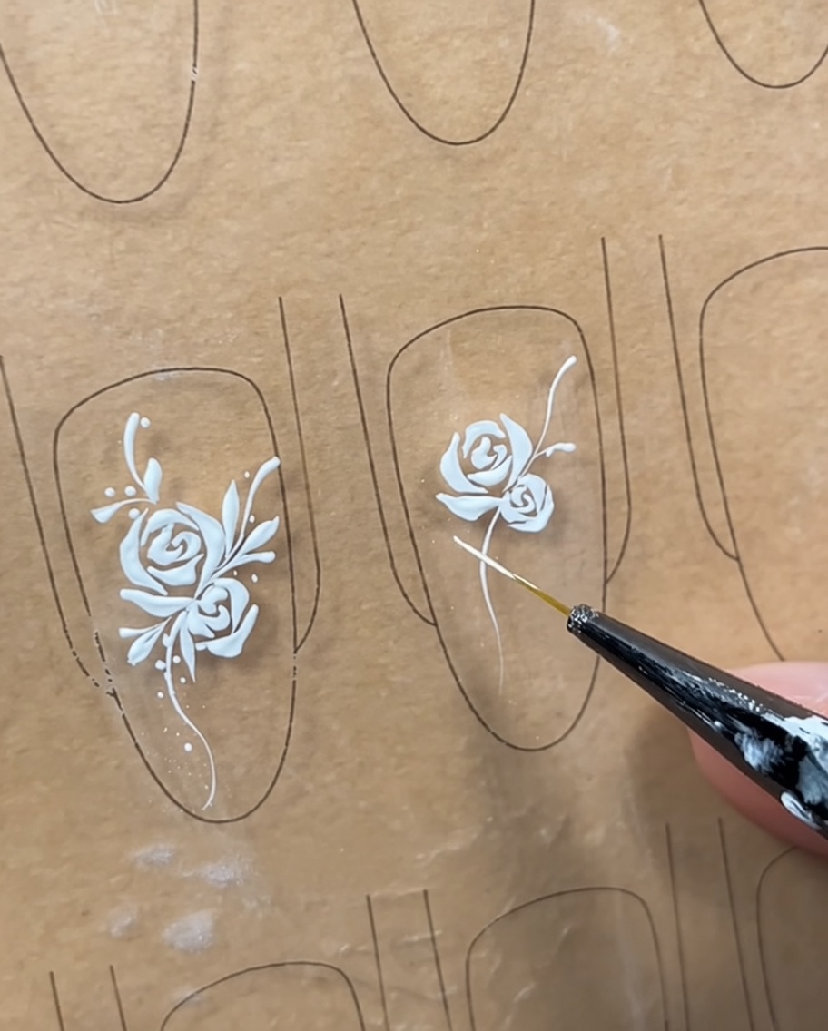A nail design featuring a rose and a vine, with initial structural lines drawn to mark where the leaves will be placed.