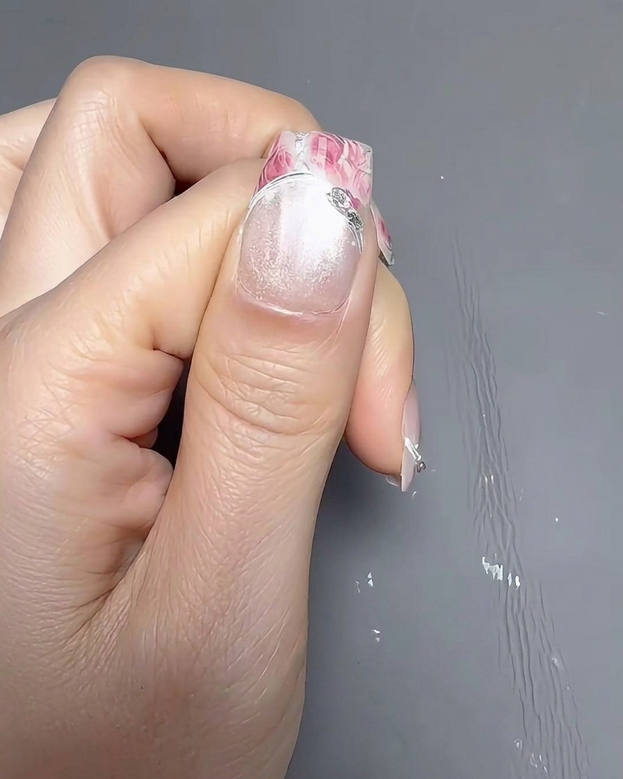 A close-up view of a brush applying a smooth coat of opaque white nail polish onto a natural nail.