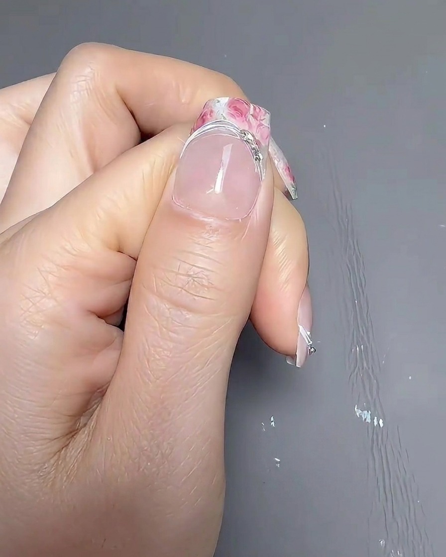 A hand resting inside a professional UV/LED nail lamp with the light illuminated, curing the nails.