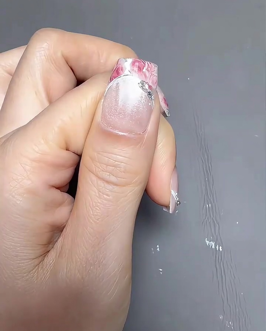 Applying a clear transfer gel to the French tip portion of the nail using a small detail brush.