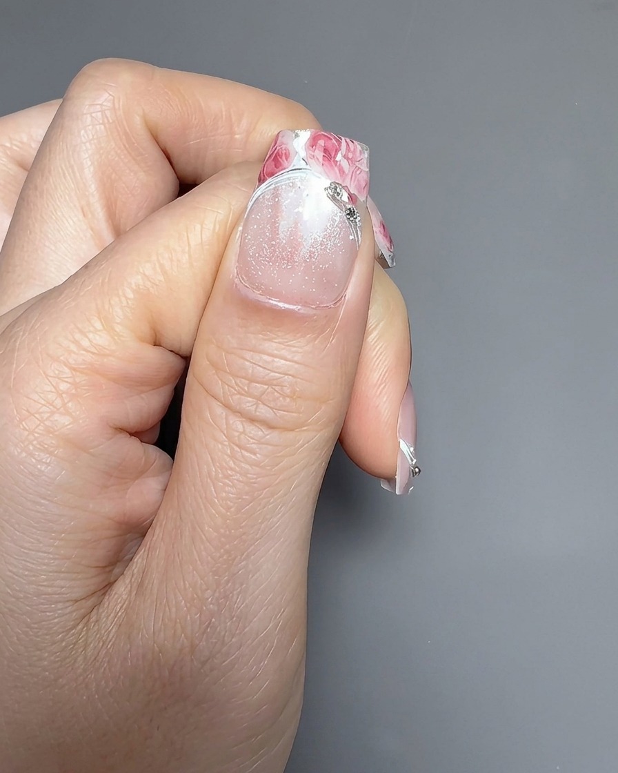 A close-up showing a second rose sticker being carefully placed over the first one on a nail.